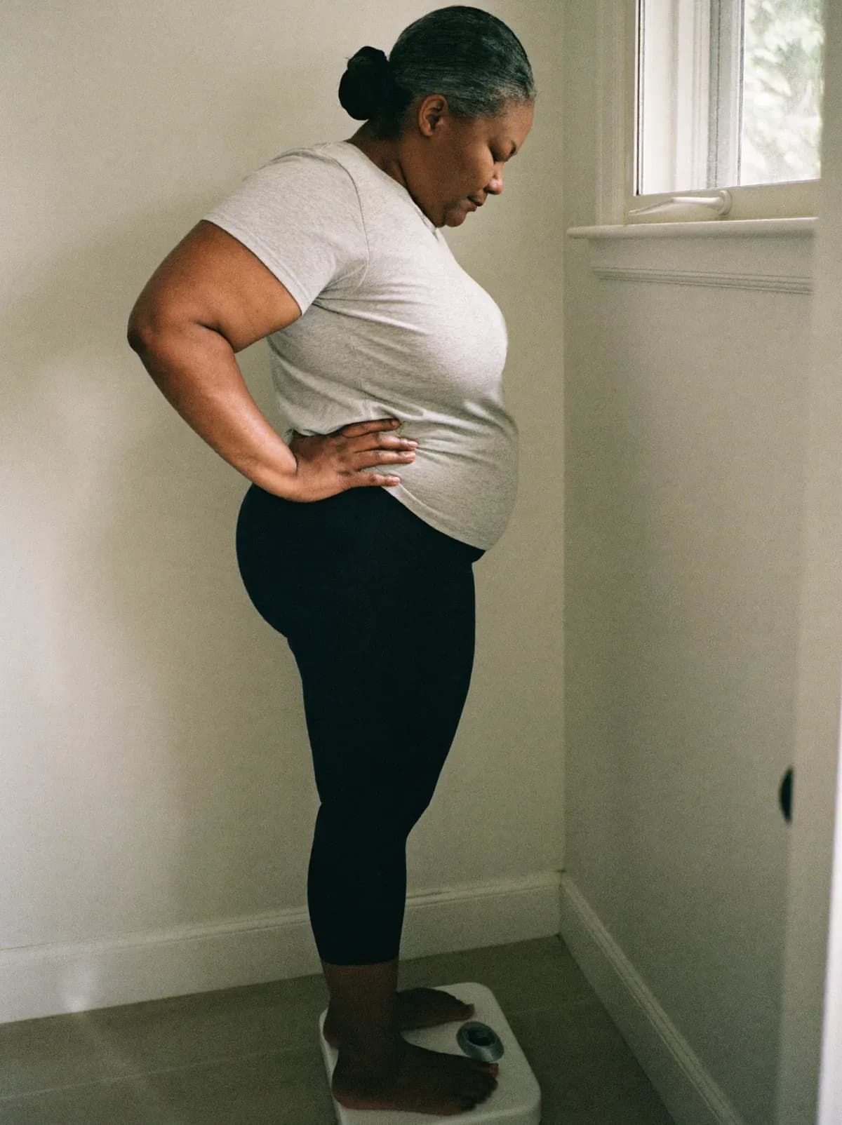 Woman standing on a bathroom scale, looking down at it quietly