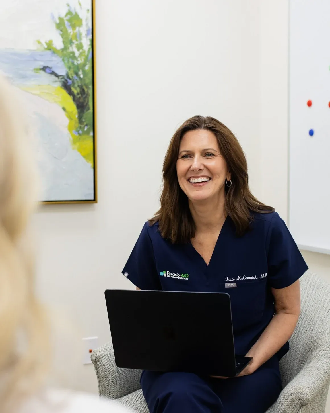 Dr. Traci McCormick, MD, laughing as she listens to a patient in her office