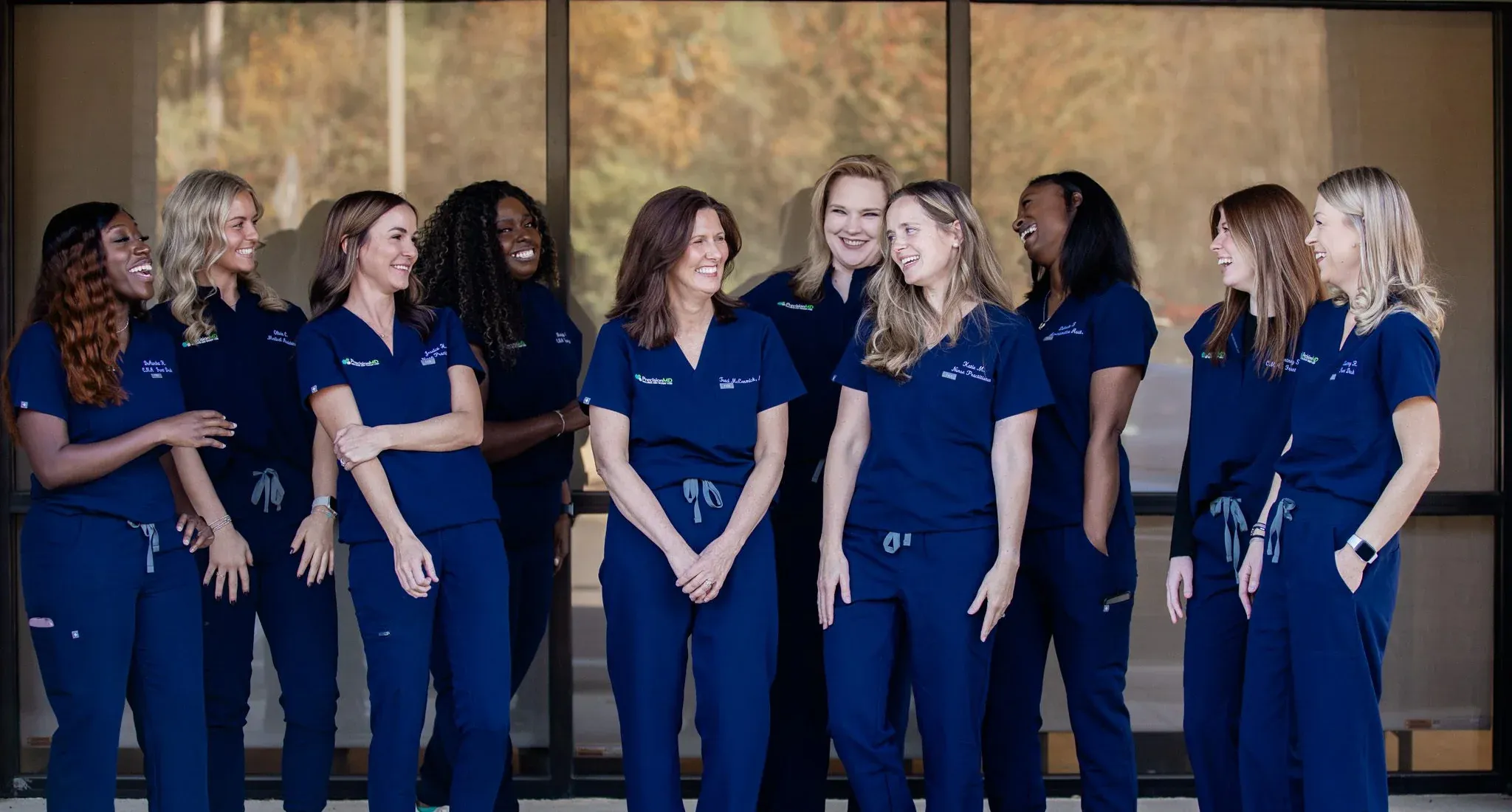 The PrecisionMD team in navy scrubs, laughing together outside the clinic